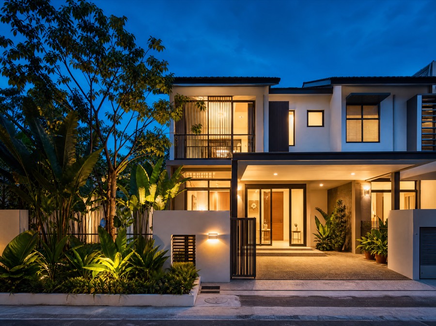A two-storey terrace house at dusk with warm light glowing through the windows.